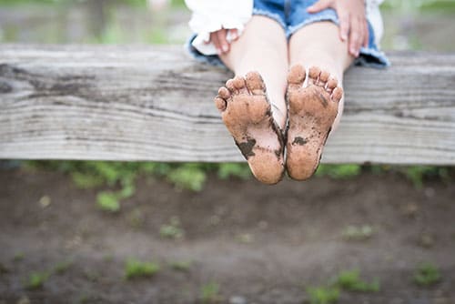 child sitting on log with muddy feet child sitting on log with muddy feet