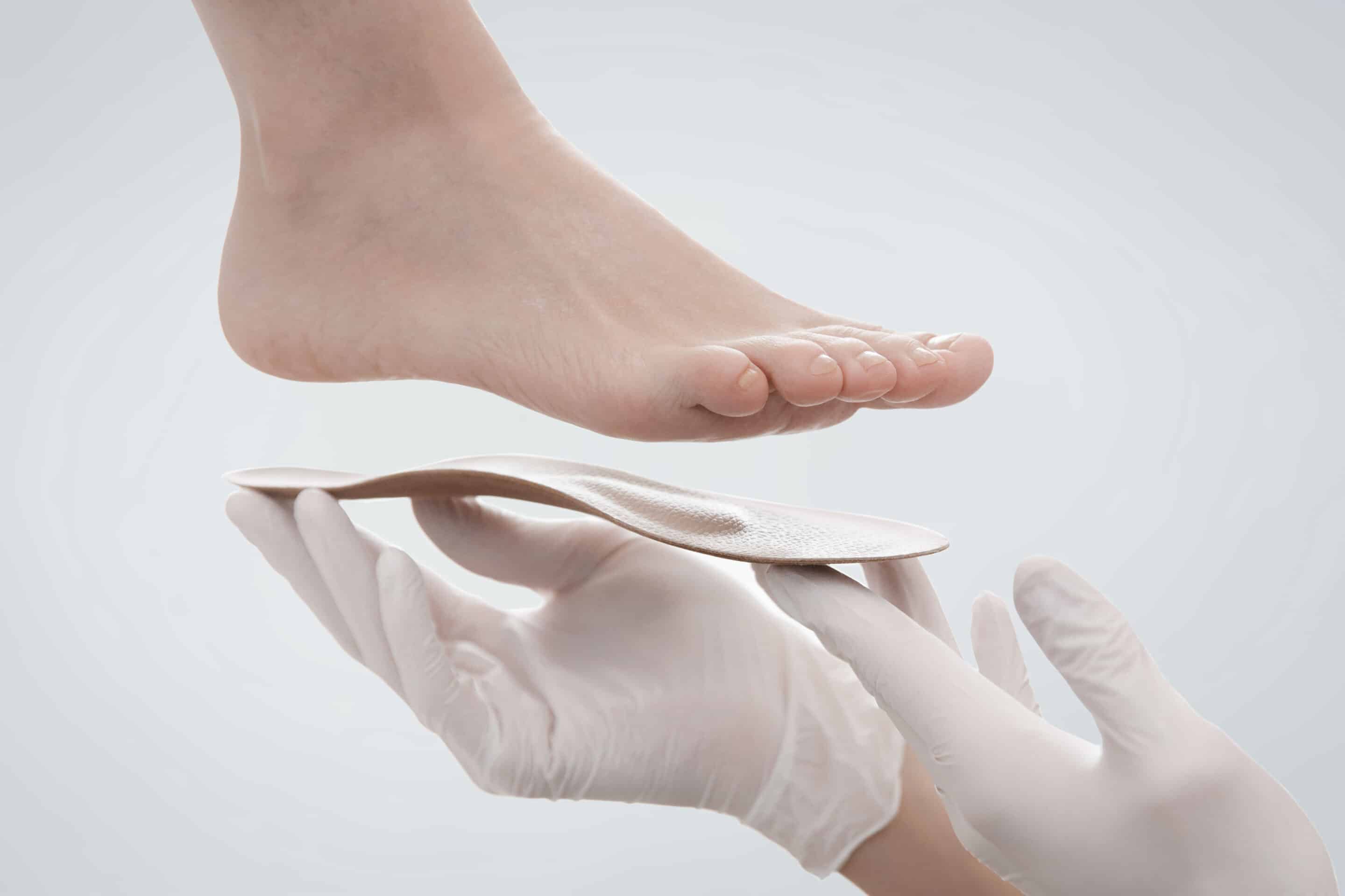 insole isolated on a white background. Hands in rubber gloves hold an orthopedic insole. Foot care, comfort for the feet. Doctor orthopedist tests the medical device. Flat feet